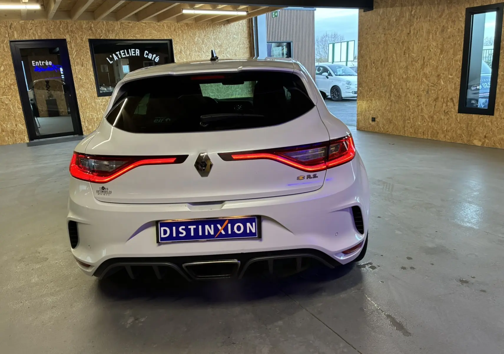 Vue arrière d'une Renault Mégane IV RS 280 EDC6 blanche, avec feux LED allumés et double sortie d'échappement centrale.