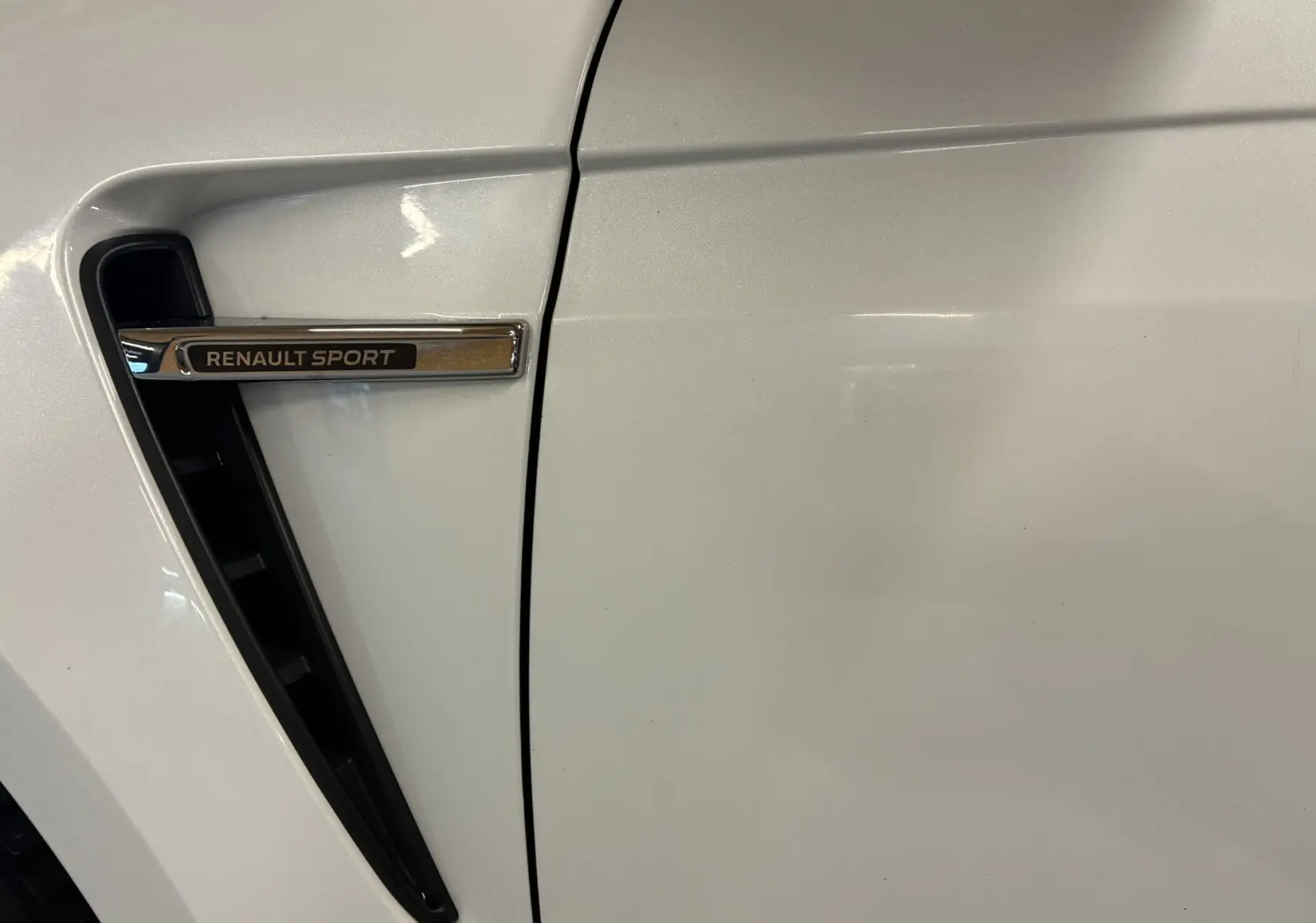 Gros plan sur la prise d'air latérale gauche blanche avec l’inscription chromée Renault Sport sur une Renault Mégane IV RS 280 EDC6.