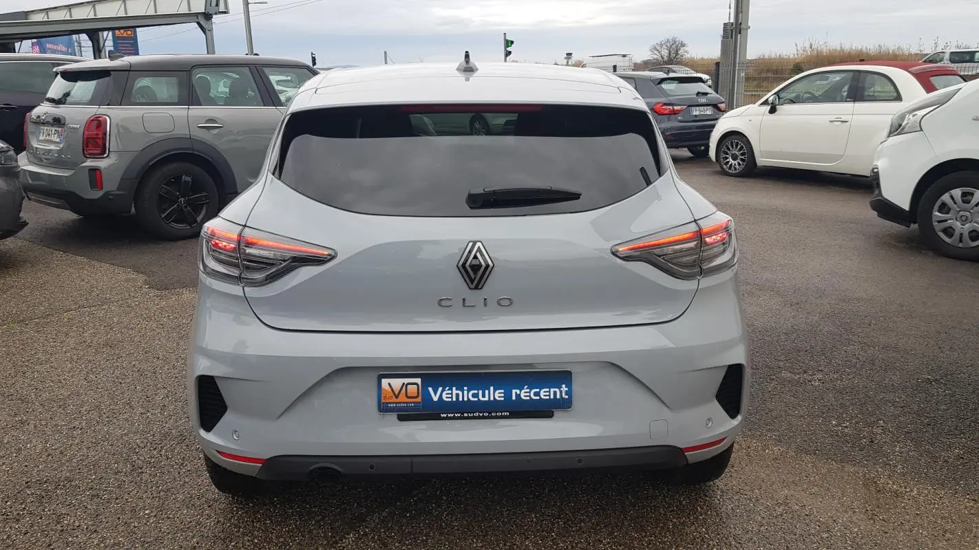 Vue arrière d'une Renault Clio gris clair 2025 avec feux LED allumés et vitres arrière surteintées.