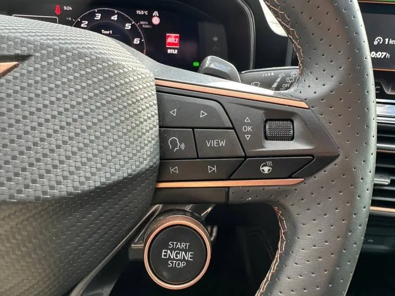 Gros plan sur le volant perforé et les commandes multifonctions du CUPRA Formentor gris, avec bouton start/stop visible.