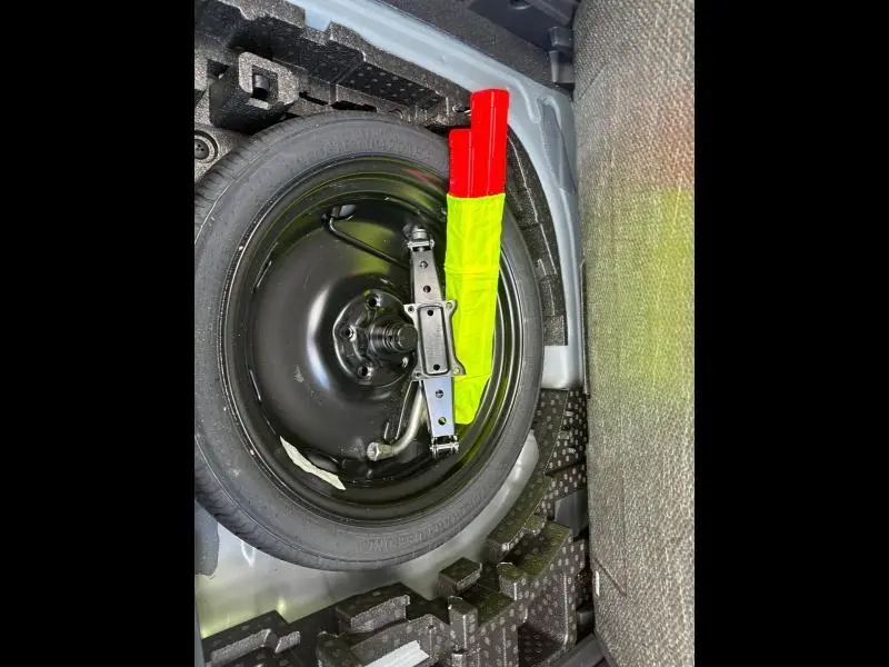 Vue plongeante sur la roue de secours noire et le triangle de signalisation rouge et jaune dans le coffre du CUPRA Formentor 2025.