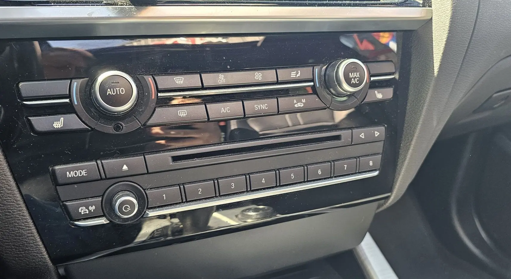 Gros plan sur la console centrale noire du BMW X4 xDrive20dA 2015, mettant en valeur les commandes de climatisation et audio.