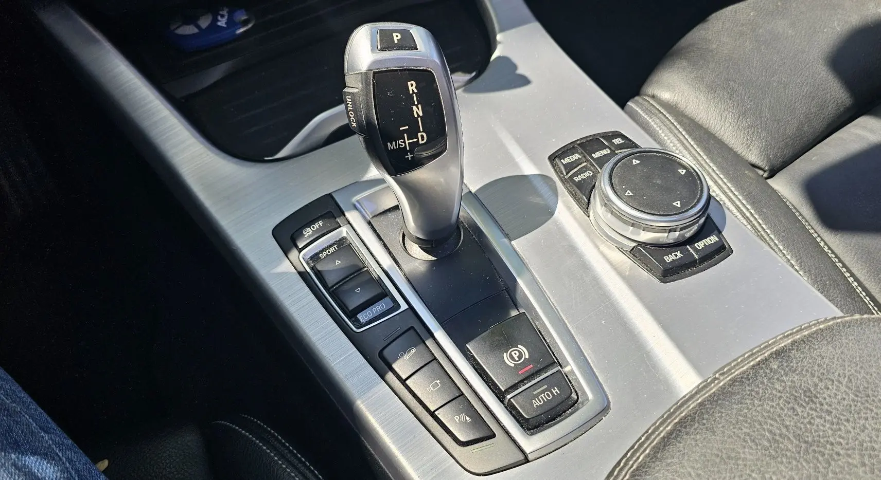 Gros plan sur la console centrale argentée du BMW X4 xDrive20d noir, avec levier de vitesse et commandes multimédia.