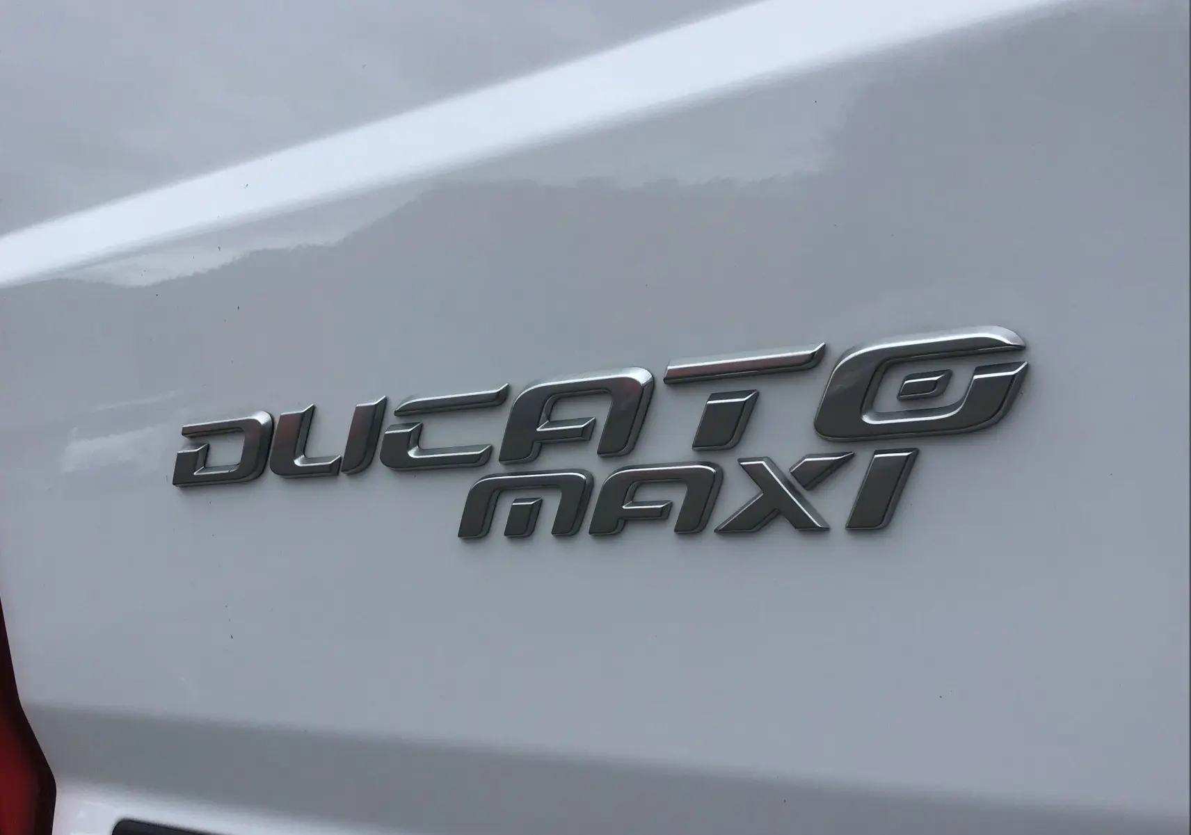 Gros plan sur l’inscription argentée "Ducato Maxi" sur la carrosserie blanche arrière du FIAT Ducato Fourgon.