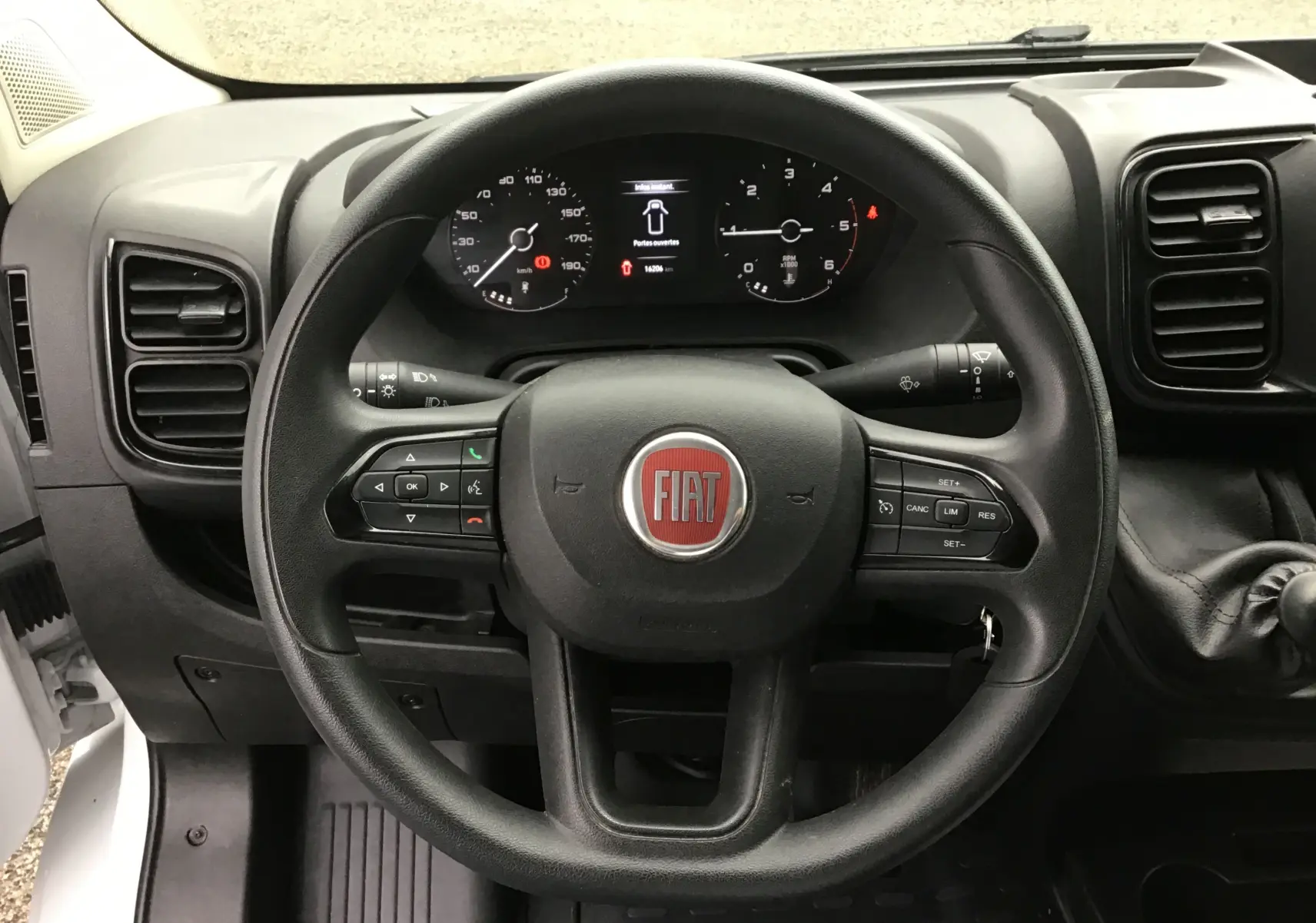 Vue rapprochée du volant noir du Fiat Ducato Fourgon 2024 avec tableau de bord numérique et commandes intégrées.