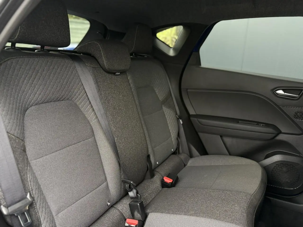 Vue intérieure côté droit des sièges arrière gris foncé du Renault Captur 2025 avec ceinture de sécurité et garnitures de porte.