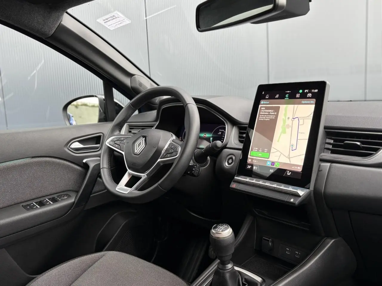 Vue intérieure côté conducteur du Renault Captur 2025 avec tableau de bord numérique et écran tactile vertical.