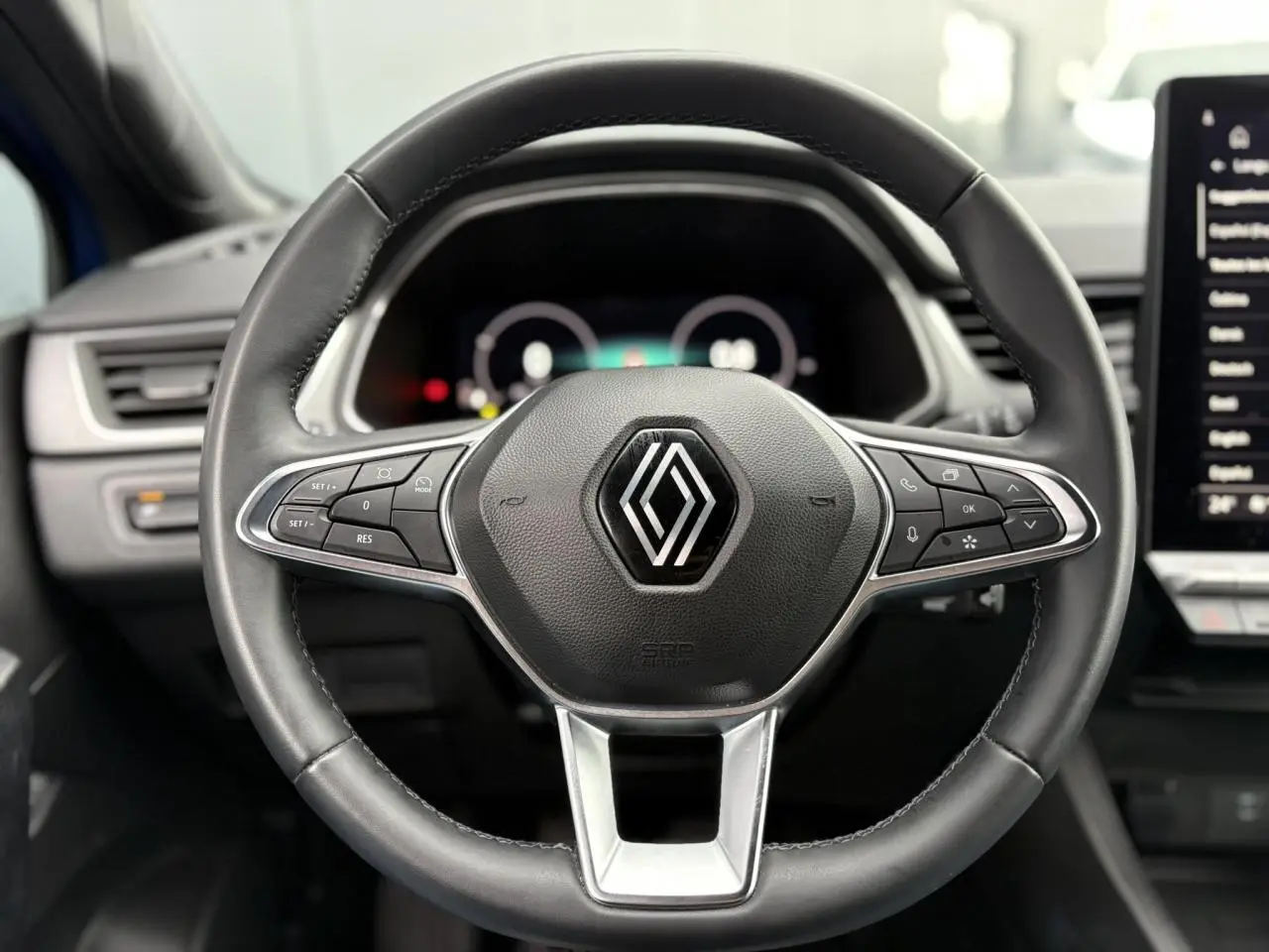 Vue centrée sur le volant cuir noir du Renault Captur 2025 avec commandes intégrées et tableau de bord numérique flou.