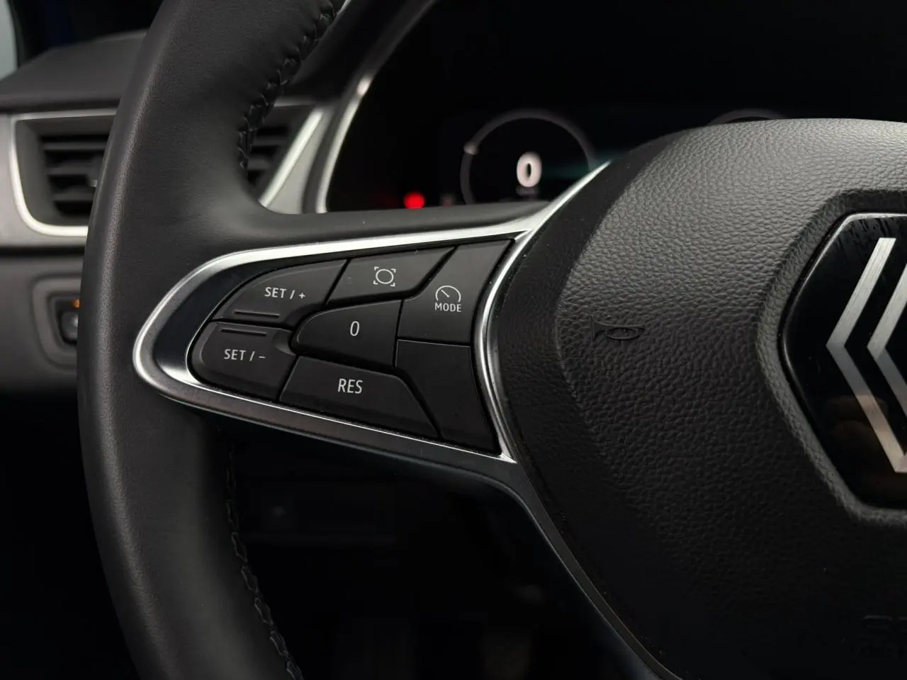 Gros plan sur le volant noir du Renault Captur 2025, mettant en valeur les commandes de régulateur de vitesse côté gauche.