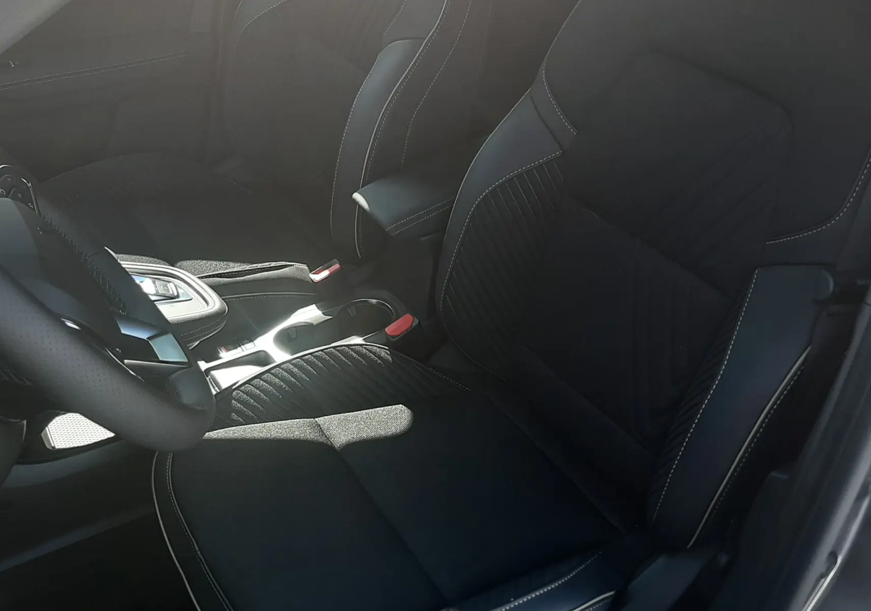 Vue intérieure côté conducteur du Renault Symbioz 2025, sièges noirs avec surpiqûres contrastantes et console centrale moderne.