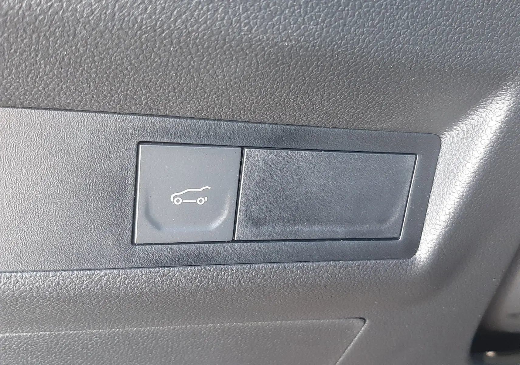 Bouton d'ouverture du coffre sur tableau de bord noir du Renault Symbioz E-Tech Full Hybrid gris Cassiopée.