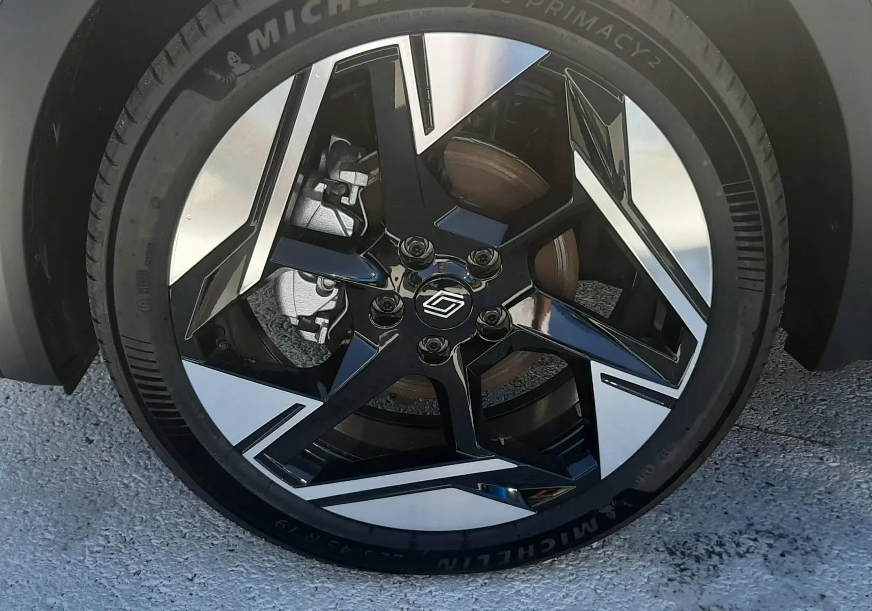 Gros plan sur la roue avant droite du Renault Symbioz gris Cassiopée, jante alliage noir et argent au design moderne.