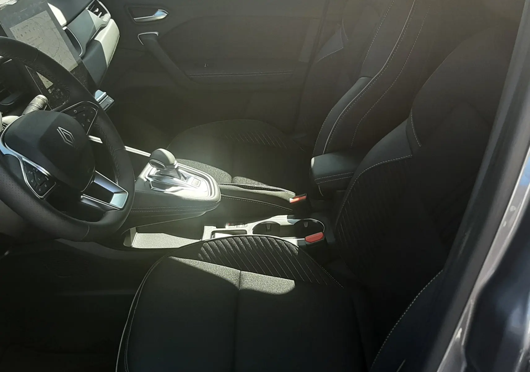 Intérieur noir de la Renault Symbioz E-Tech, vue côté gauche montrant sièges avant et console centrale avec levier de vitesse.