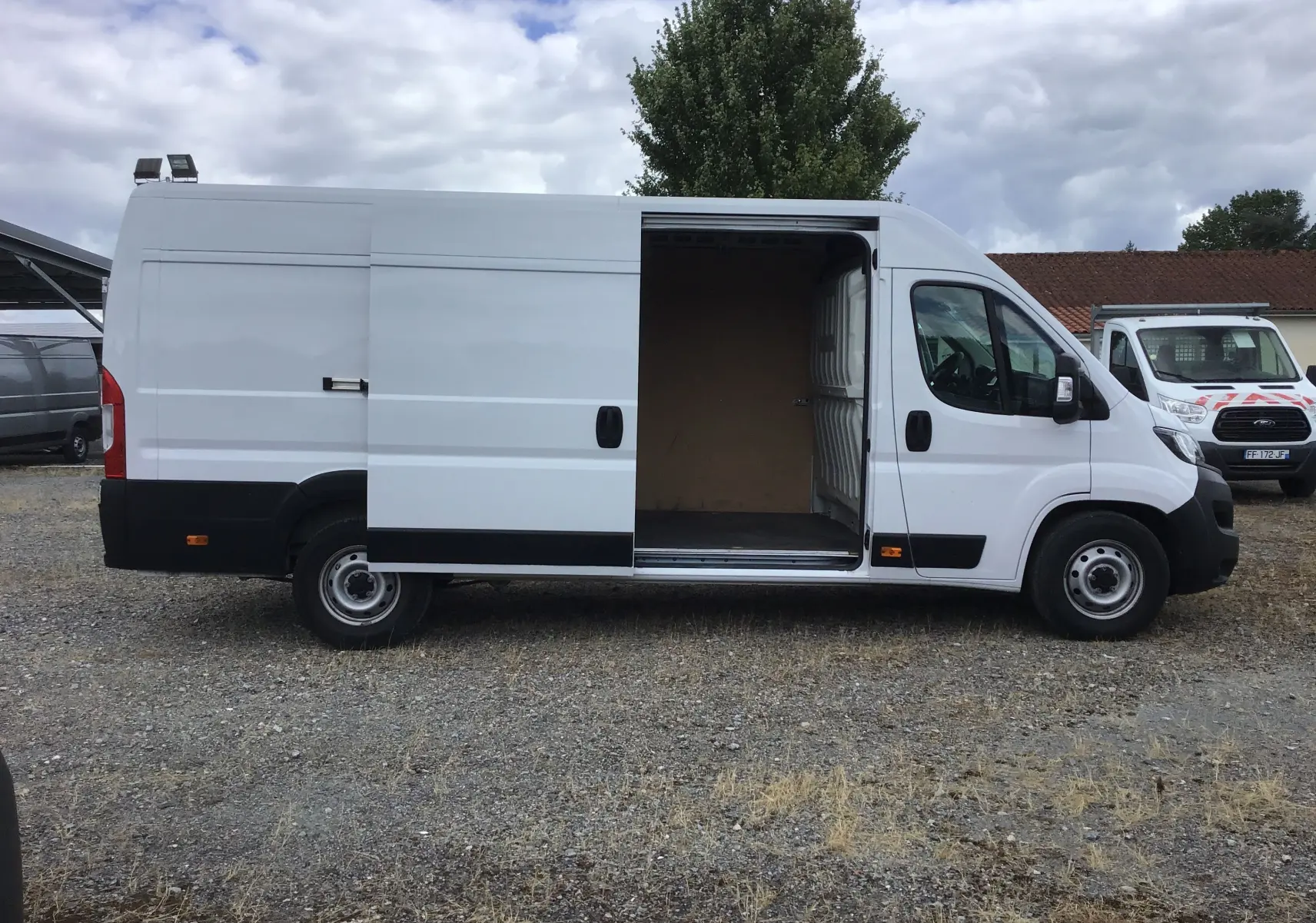 Fiat Ducato Fourgon blanc 2024 vu de profil côté gauche, porte latérale coulissante ouverte dévoilant l’intérieur vide.