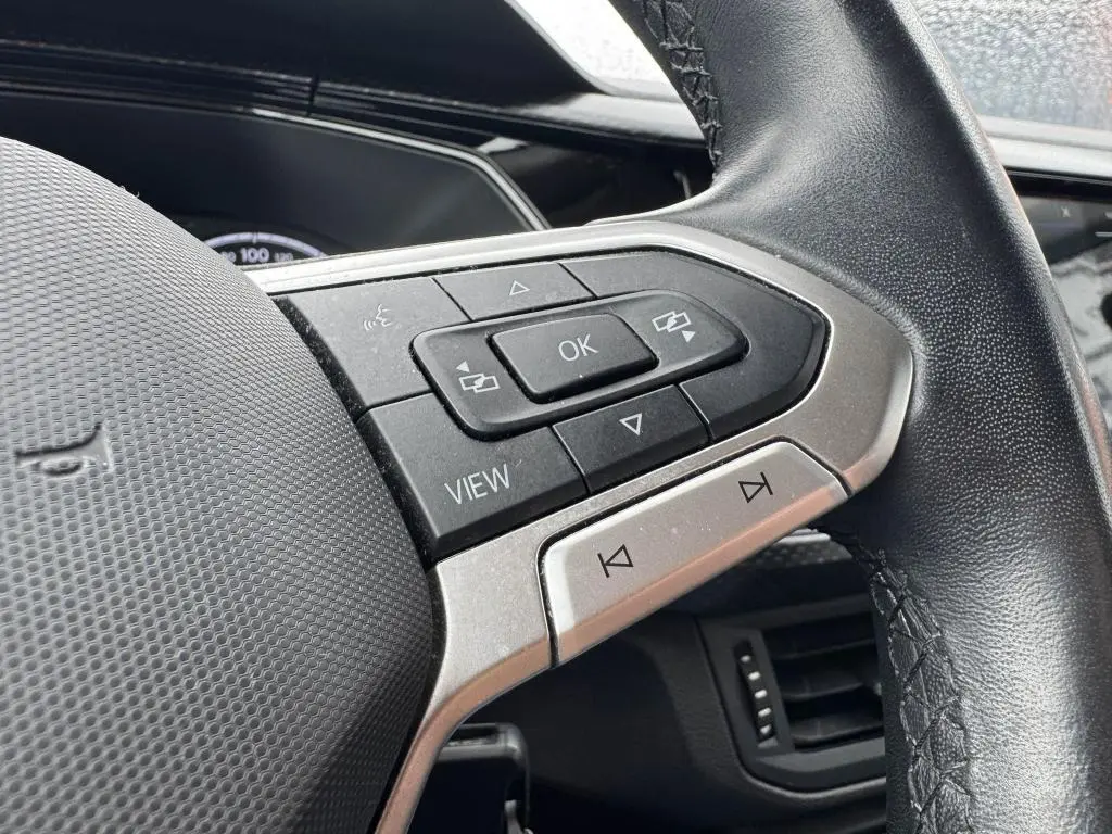 Gros plan sur les commandes multifonctions côté gauche du volant en cuir noir du Volkswagen T-Cross orange 2021.