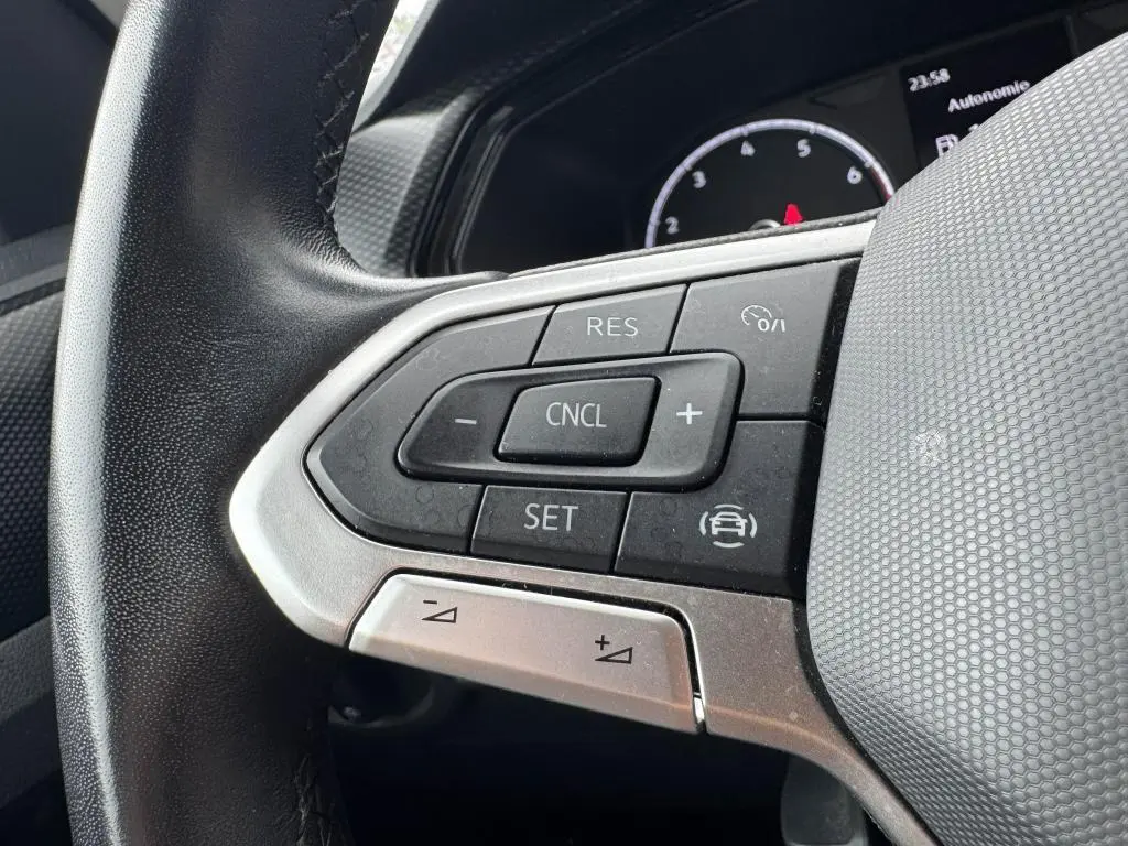 Gros plan sur les commandes de régulateur de vitesse au volant cuir noir du Volkswagen T-Cross orange 2021.