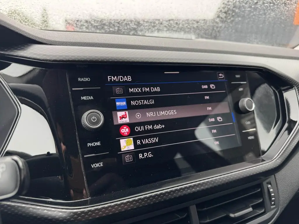 Écran tactile central du Volkswagen T-cross 1.0 TSI 110 Active affichant les stations FM/DAB avec commandes autour.