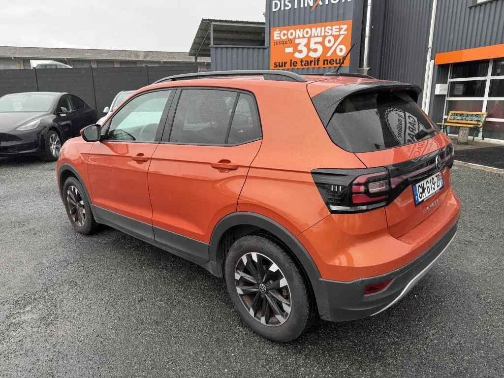 Volkswagen T-Cross orange métallisé vue 3/4 arrière droit avec jantes Galway et feux arrière noirs.