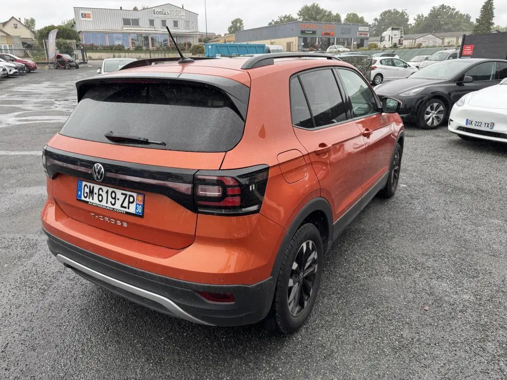 Volkswagen T-Cross orange métallisé vue 3/4 arrière droit, avec feux arrière noirs et jantes alliage Galway.
