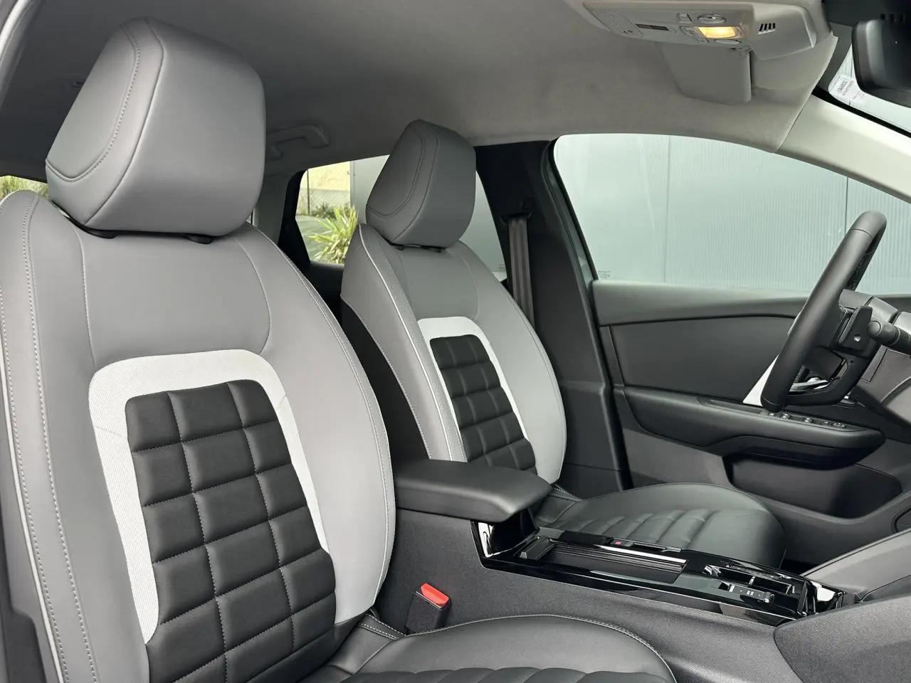 Vue intérieure côté conducteur de la Citroën C4 2025 avec sièges Advanced Comfort gris clair et noir à motifs carrés.