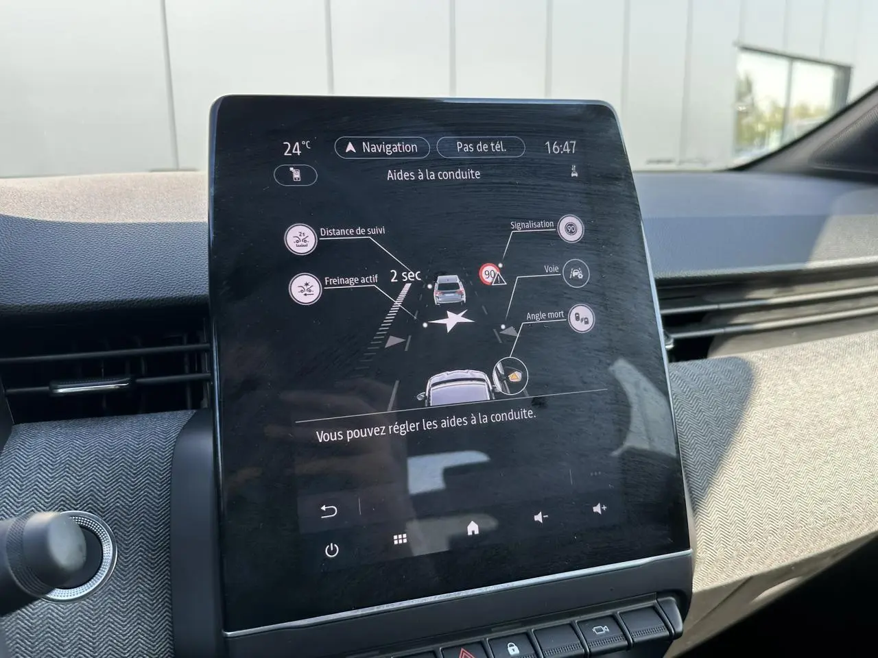 Écran tactile central de la Renault Clio 2025 affichant les aides à la conduite dans un intérieur clair.