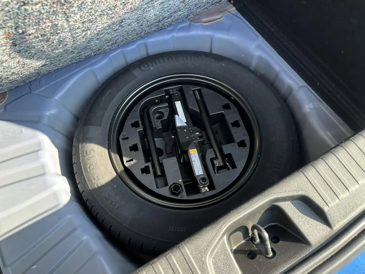 Roue de secours tôle avec outils de changement dans le coffre d'une Renault Clio TCE 90 Techno Bleu Iron 2025.