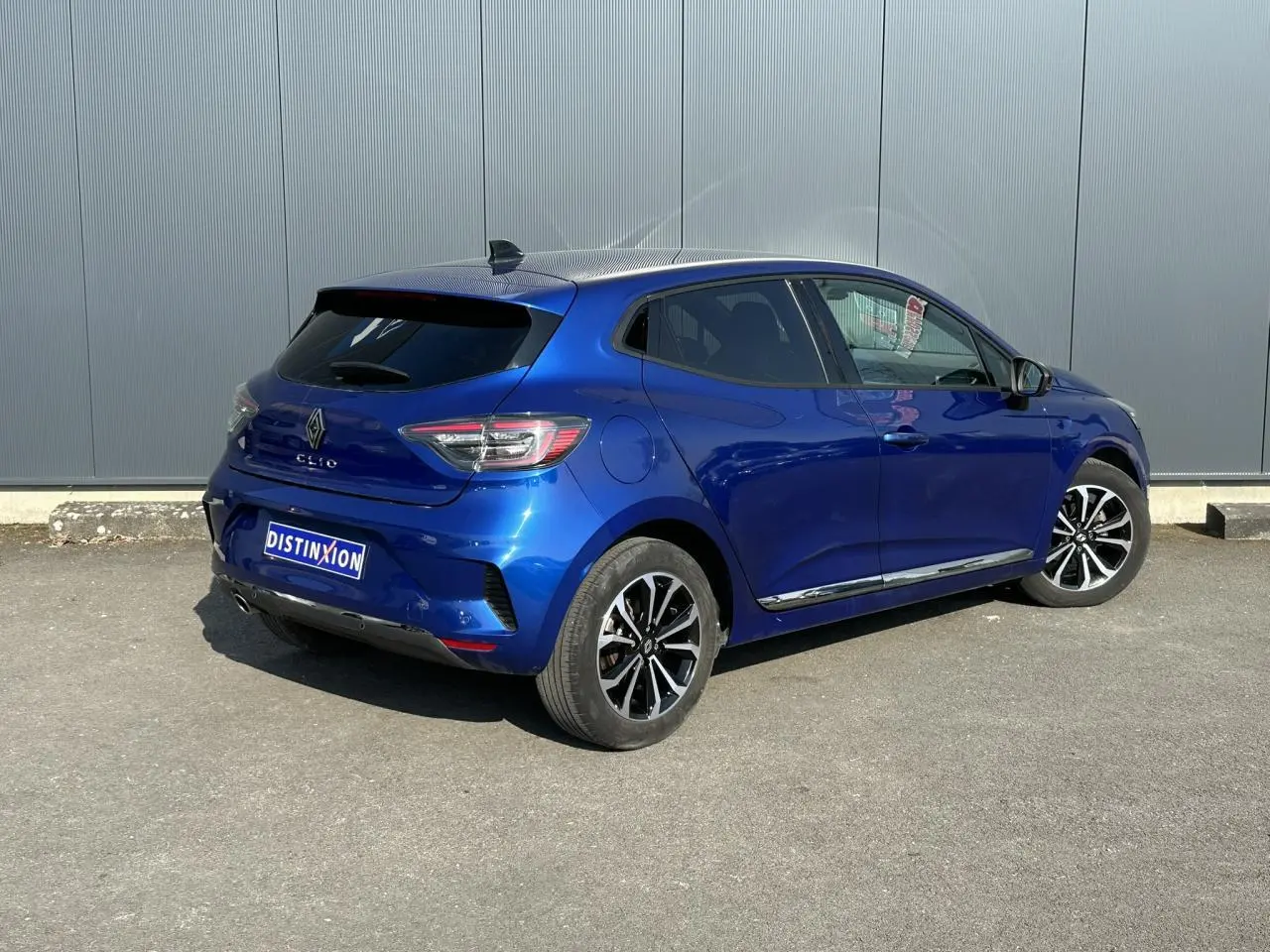 Vue 3/4 arrière droite d'une Renault Clio Bleu Iron 2025 avec jantes alliage et vitres surteintées.