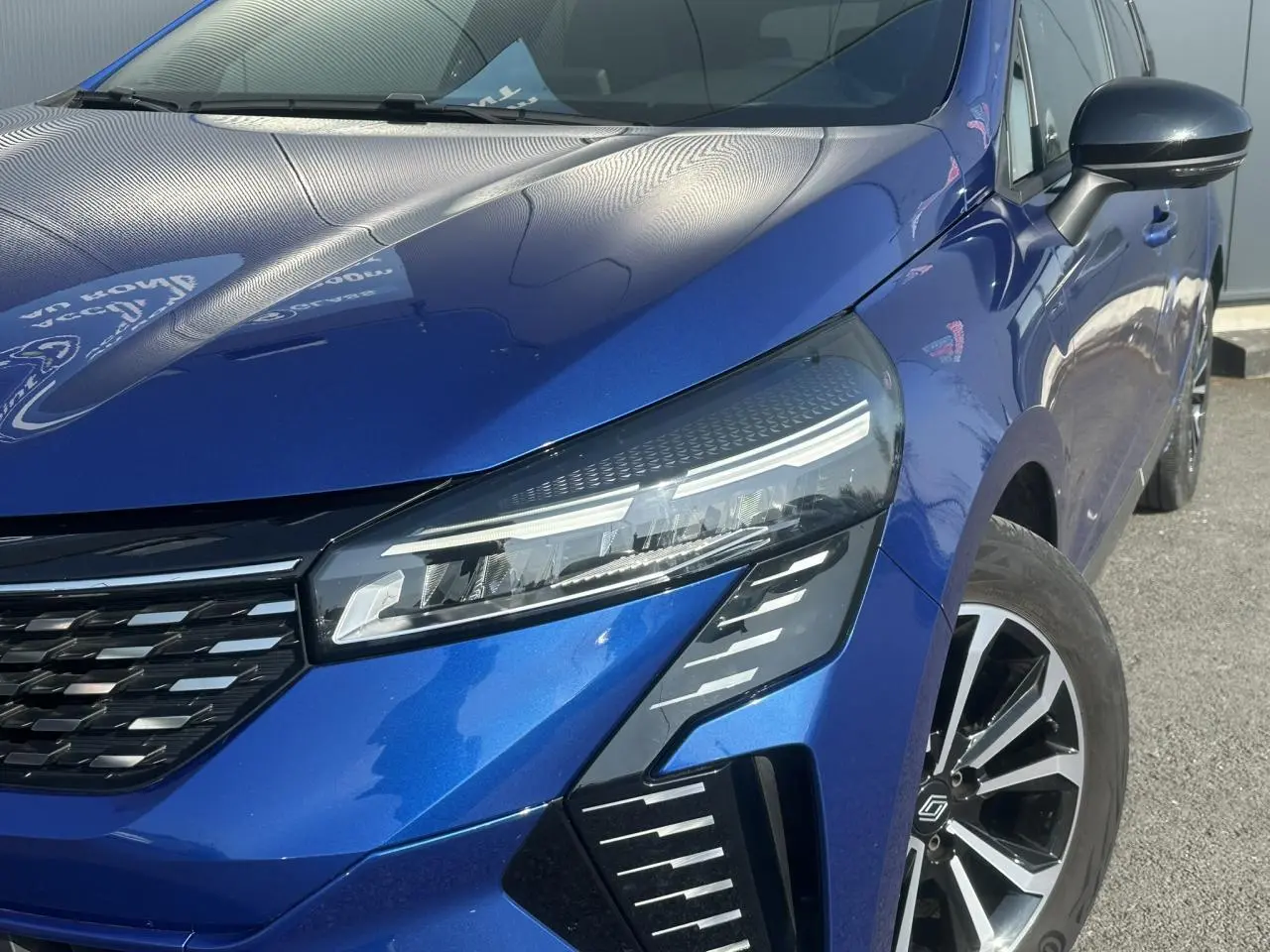 Gros plan sur l'avant droit de la Renault Clio 2025 Bleu Iron, mettant en valeur ses phares LED et la calandre moderne.