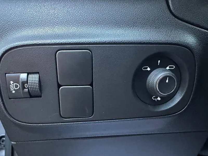 Gros plan sur les commandes de réglage des rétroviseurs et des phares d'une Citroën C3 gris 2023, version Shine.