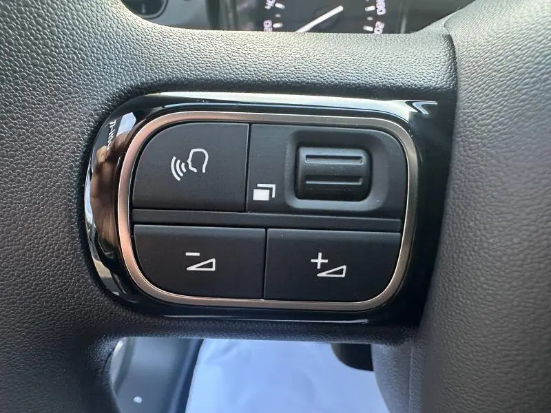 Gros plan sur les commandes du volant de la Citroën C3 2023 gris, boutons de réglage du volume et commande vocale.