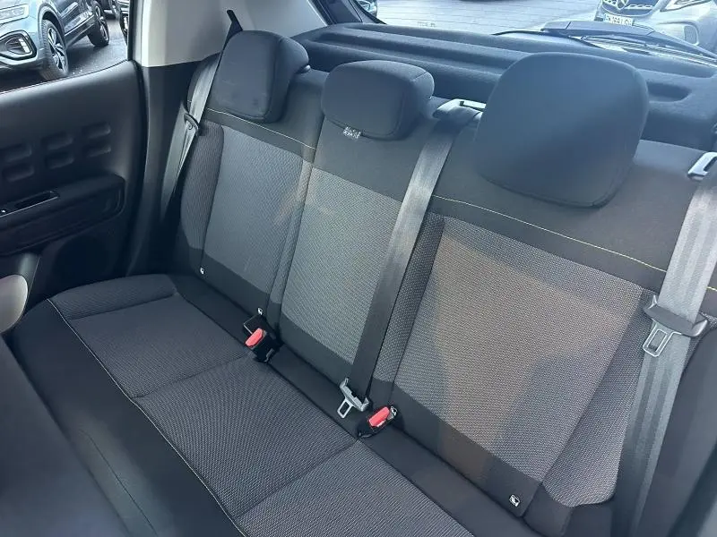 Vue intérieure montrant la banquette arrière grise de la Citroën C3 2023 avec ceintures de sécurité et appuie-têtes.