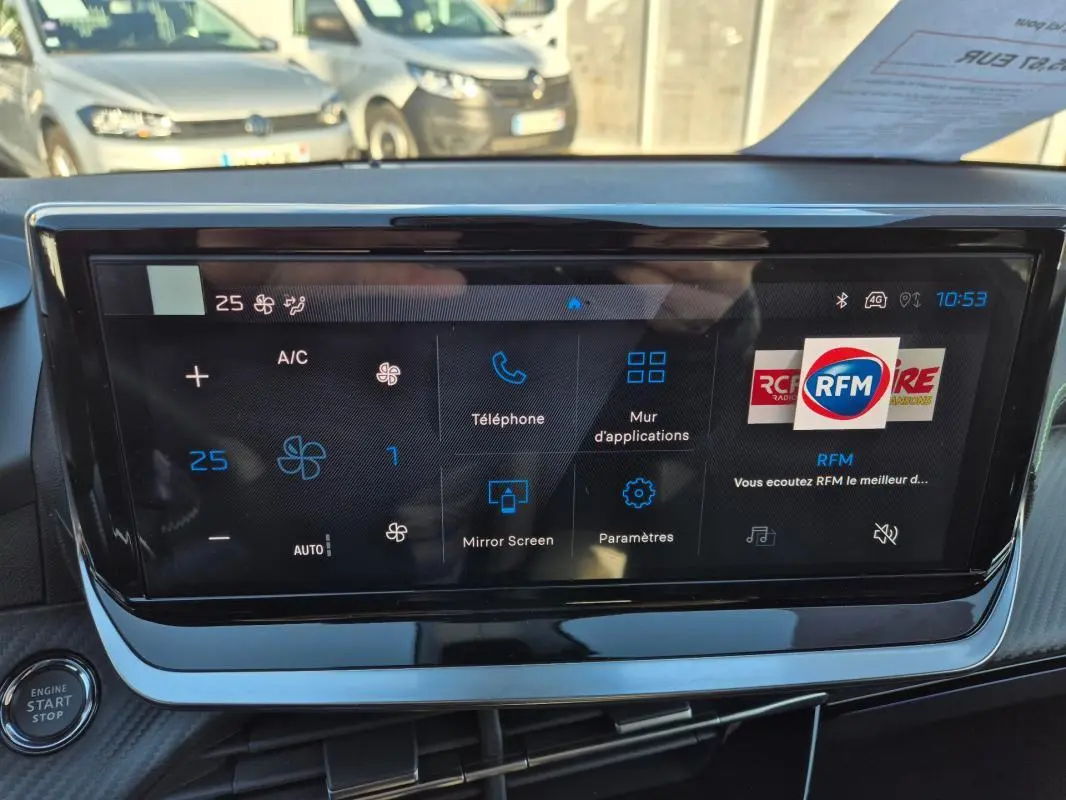 Vue rapprochée de l'écran tactile du tableau de bord de la Peugeot 208 Hybrid 136 e-DCS6 GT, affichant les commandes climatisation et multimédia.