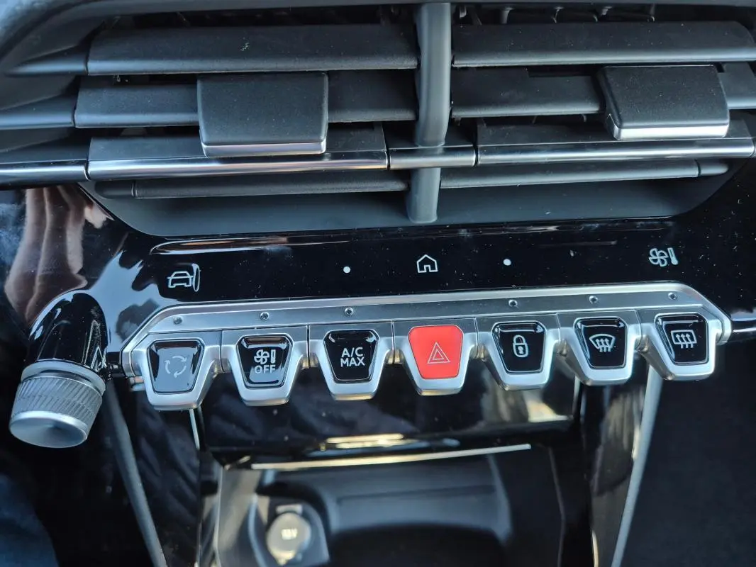 Gros plan sur la rangée de boutons de commande du tableau de bord noir brillant du Peugeot 208 Hybrid blanc.