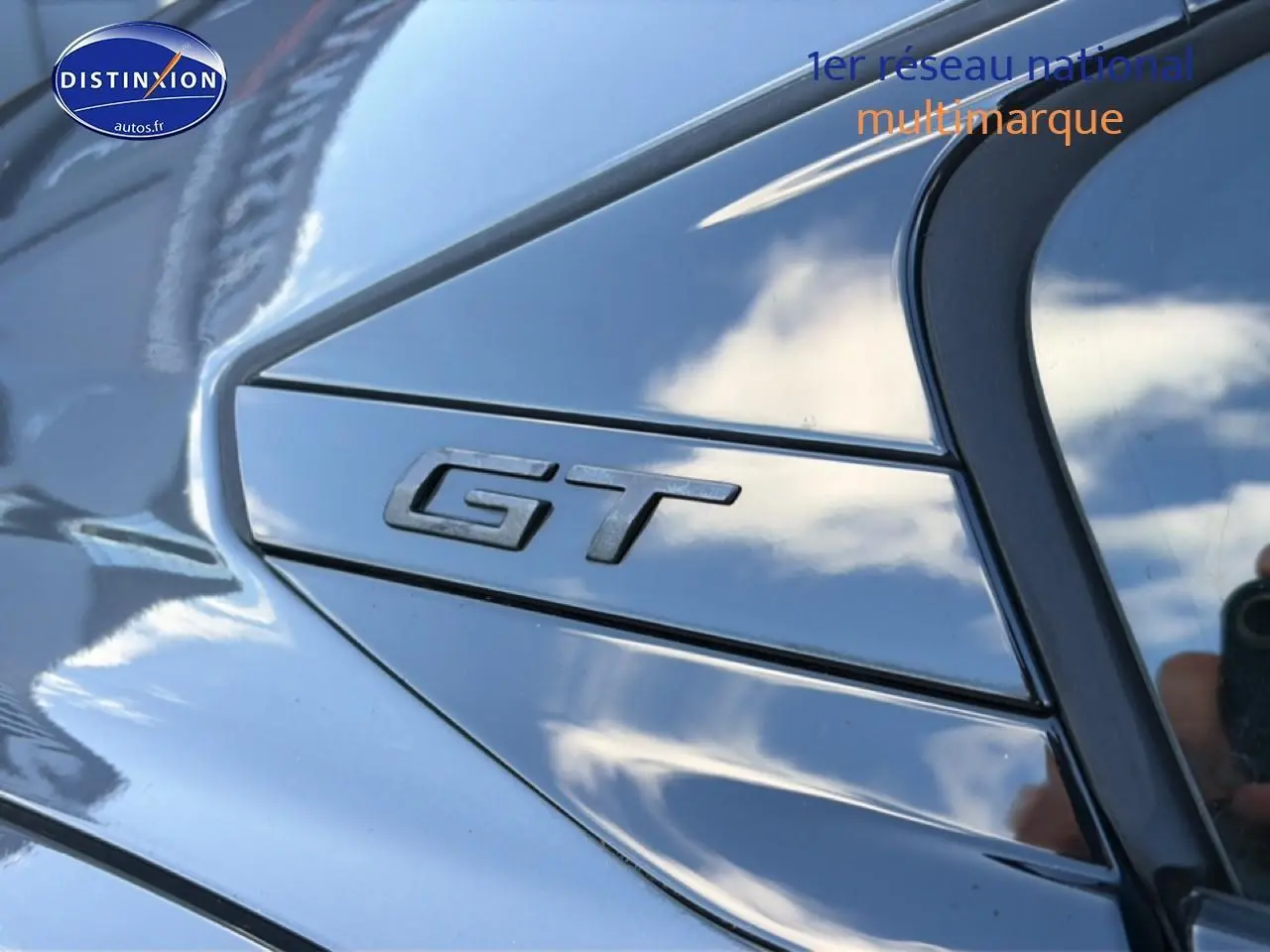 Gros plan sur l’inscription GT en relief sur la carrosserie gris titane d’une Peugeot 508 Hybrid 225 gt e-eat8.