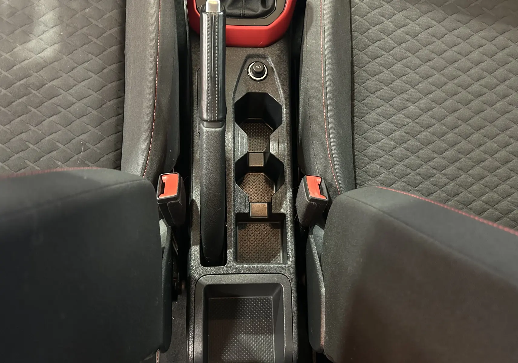 Vue plongeante sur la console centrale noire et les sièges tissu gris avec surpiqûres rouges de la Volkswagen Polo 2018.