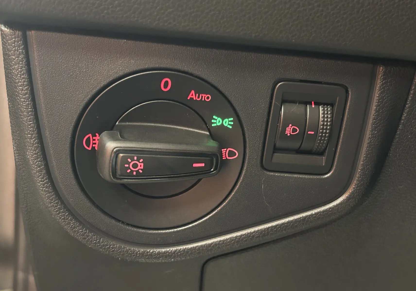 Gros plan sur le bouton de commande des phares avec réglage d'intensité dans l'habitacle d'une Volkswagen Polo gris.