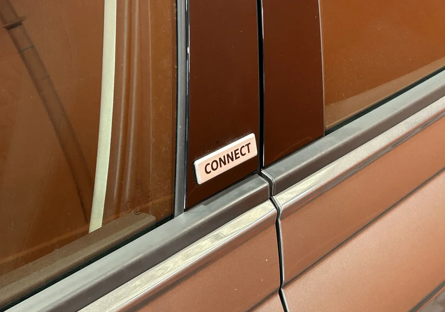 Gros plan sur l’écusson "CONNECT" sur la partie centrale noire entre les vitres d’une Volkswagen Polo gris métallisé.