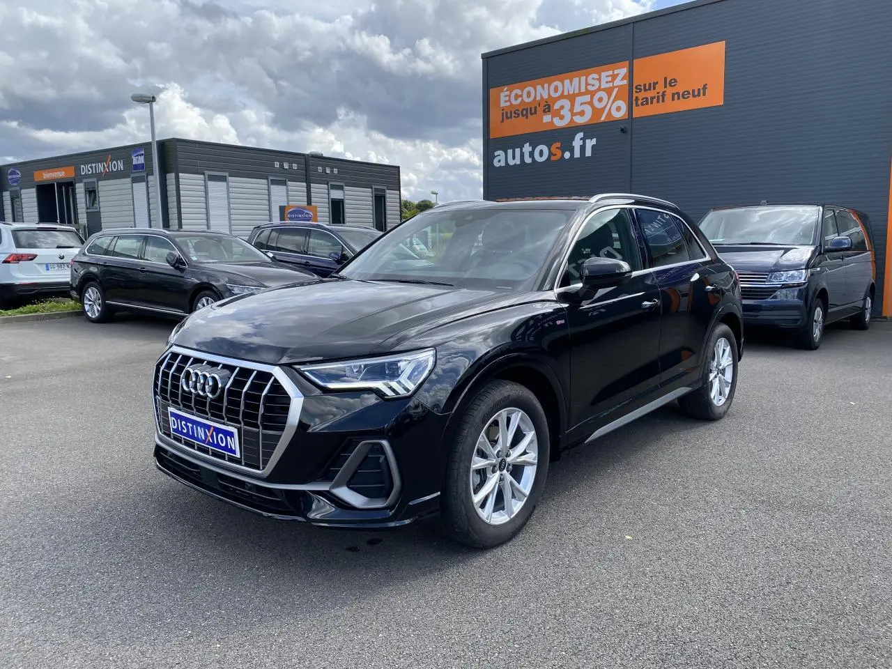 Audi Q3 noir intense métallisé vue 3/4 avant droit sur parking avec calandre chromée et jantes argentées.