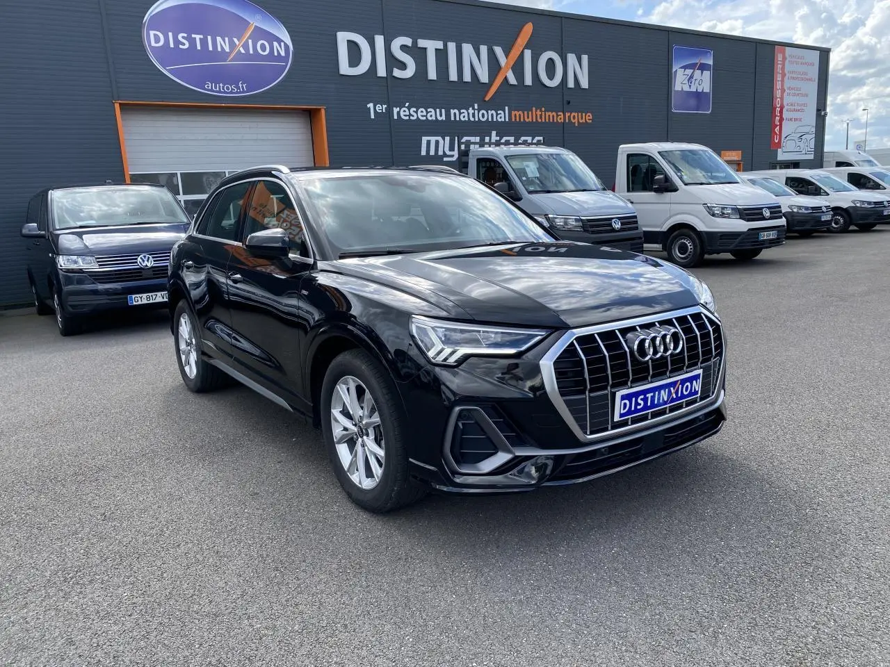 Audi Q3 noir intense métallisé vue 3/4 avant droit avec calandre chromée et jantes aluminium devant concession multimarque