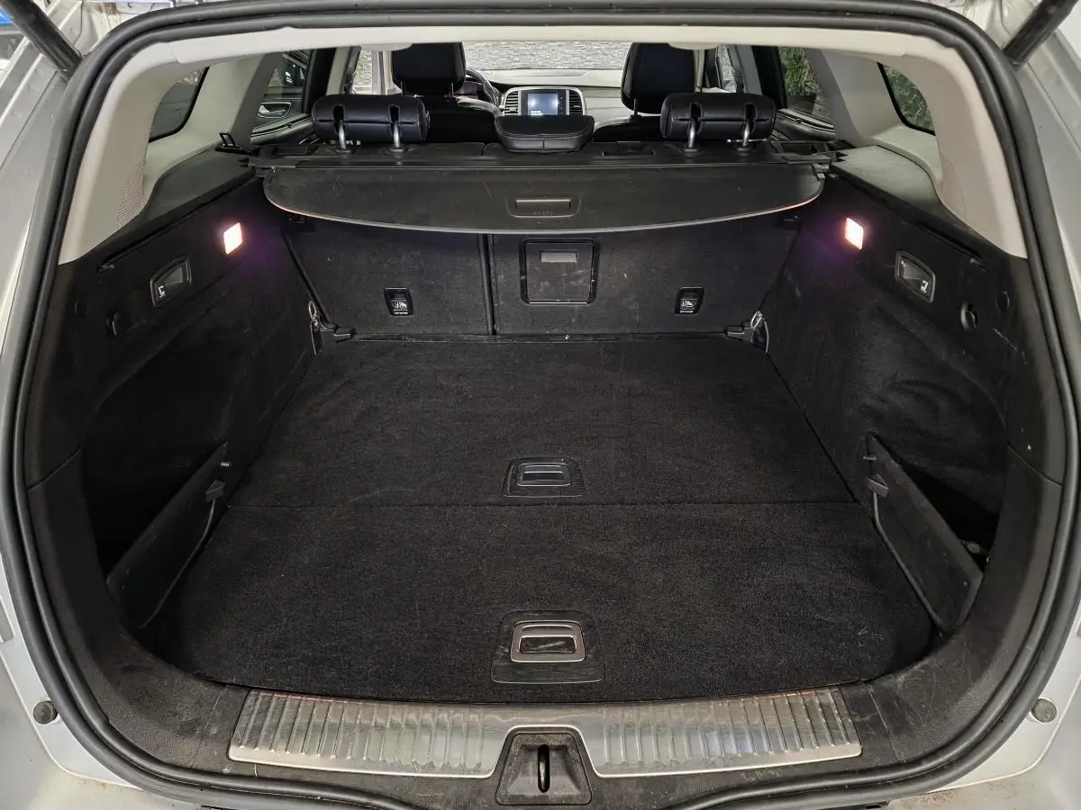 Coffre ouvert vu de l'arrière d'une Renault Talisman Estate gris, avec cache-bagages et éclairage intérieur allumé.