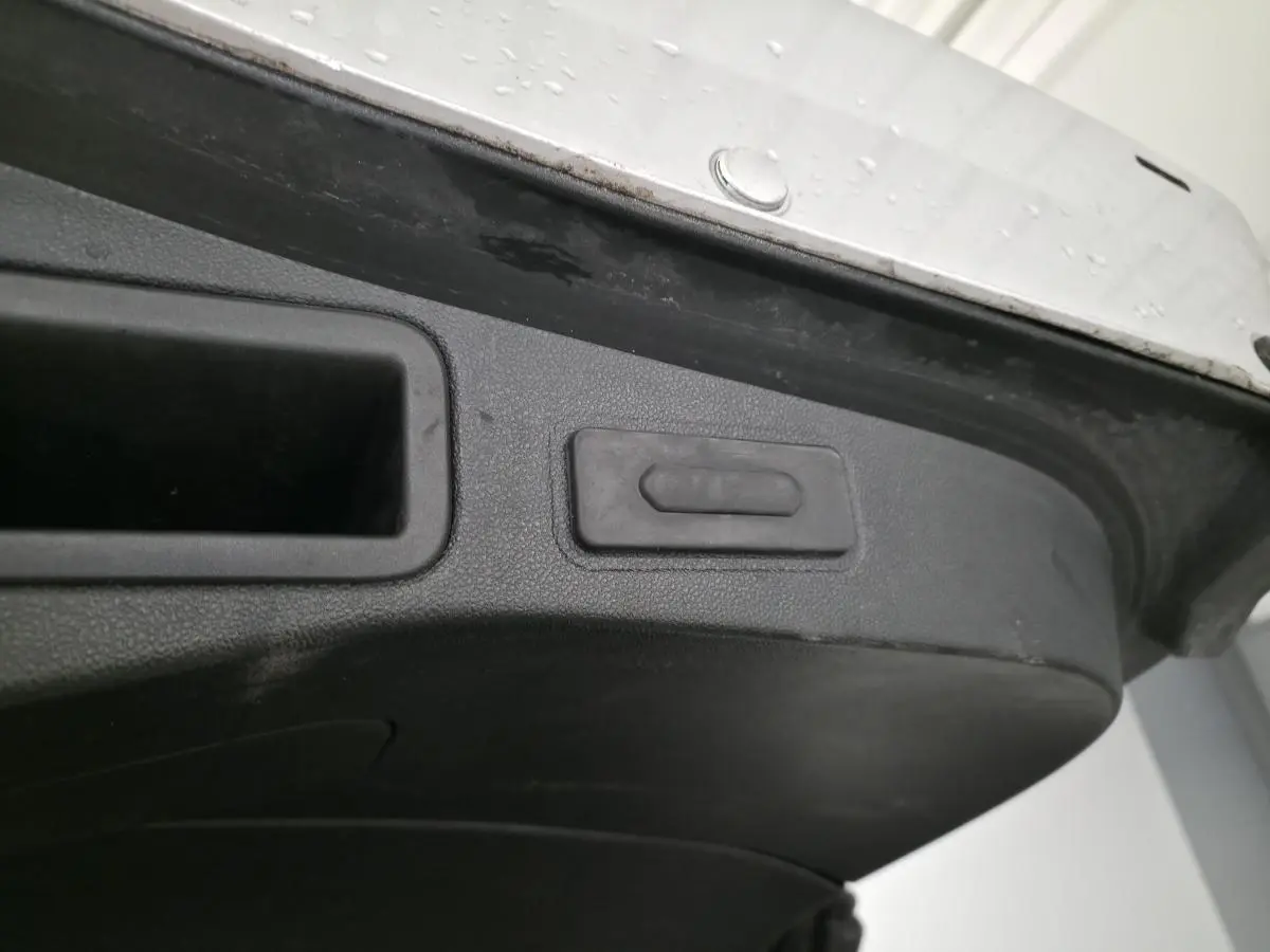 Gros plan sur le bouton d'ouverture mains-libres du hayon motorisé de la Renault Talisman Estate gris.