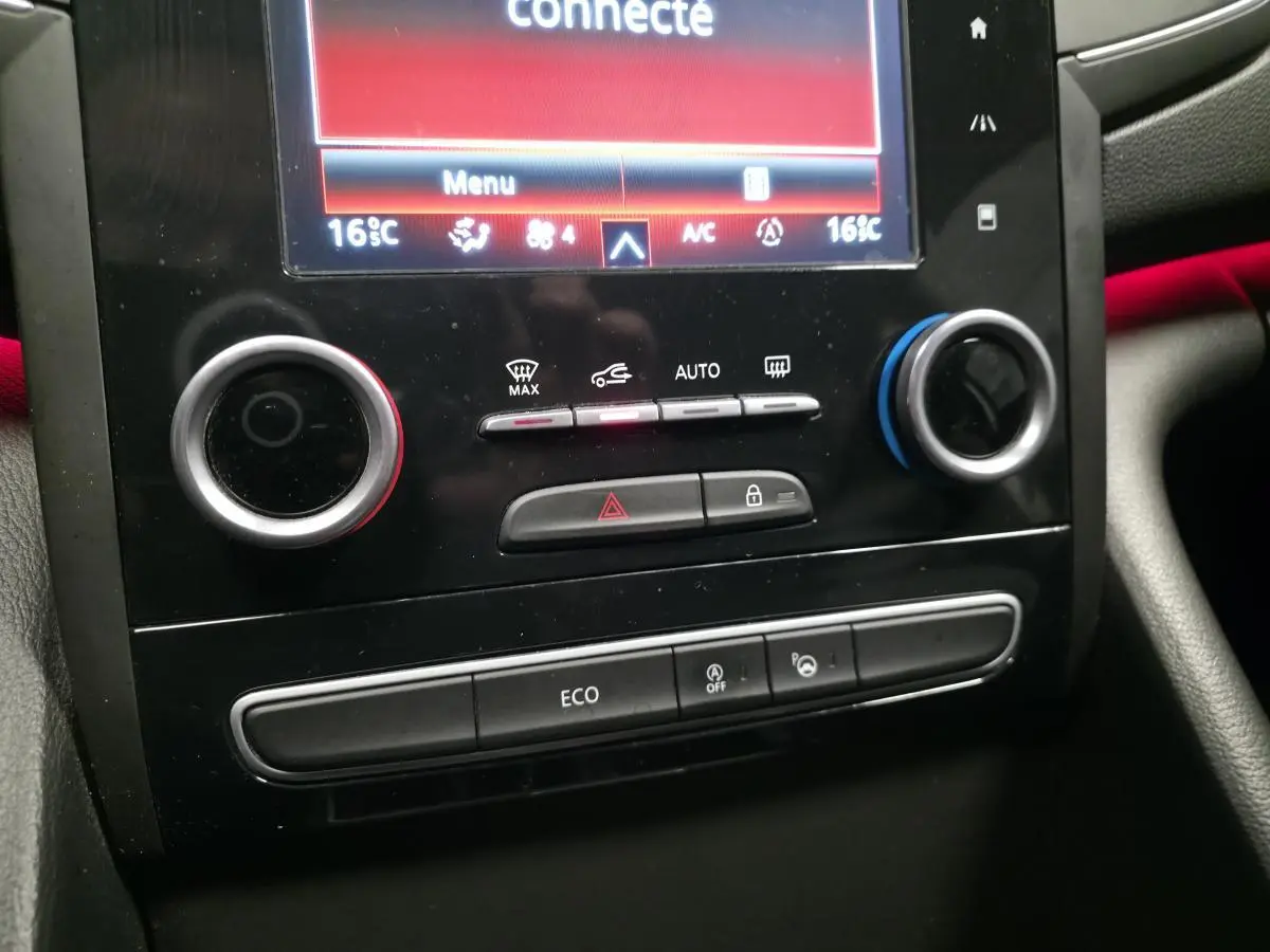 Gros plan sur la console centrale noire de la Renault Talisman Estate gris, avec commandes climatisation et écran tactile.