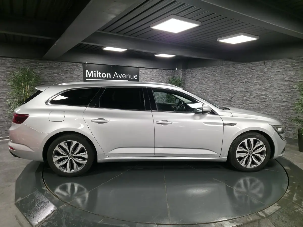 Profil droit d'une Renault Talisman Estate gris platine 2018 avec jantes alliage et vitres surteintées en showroom.