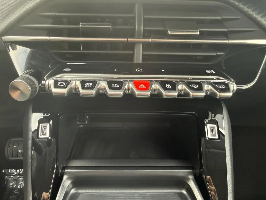 Vue rapprochée de la console centrale noire du Peugeot 208 Hybrid 145 Allure, avec boutons de commande et air vents.