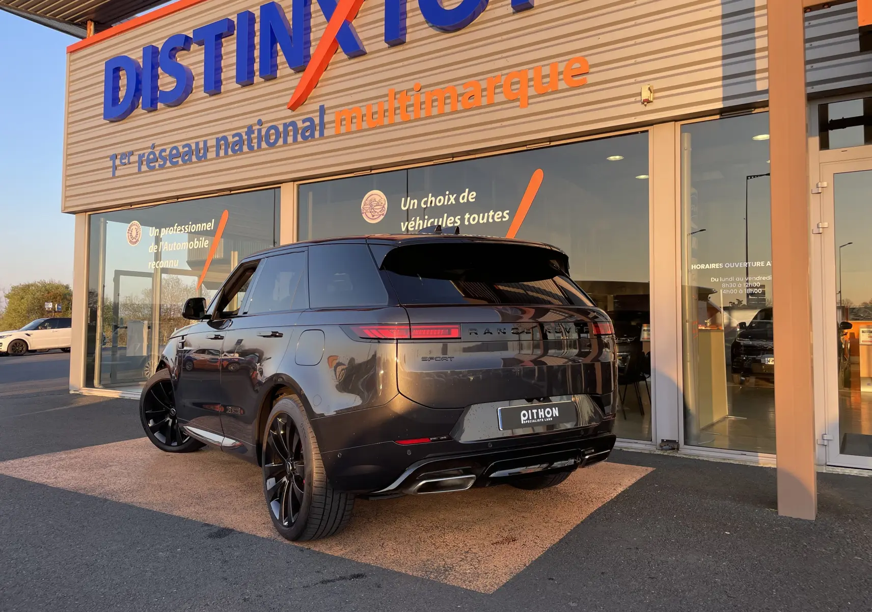 Vue 3/4 arrière droite d'un Range Rover Sport P440 HSE R-Dynamic gris Carpathian avec jantes noires et étriers rouges.