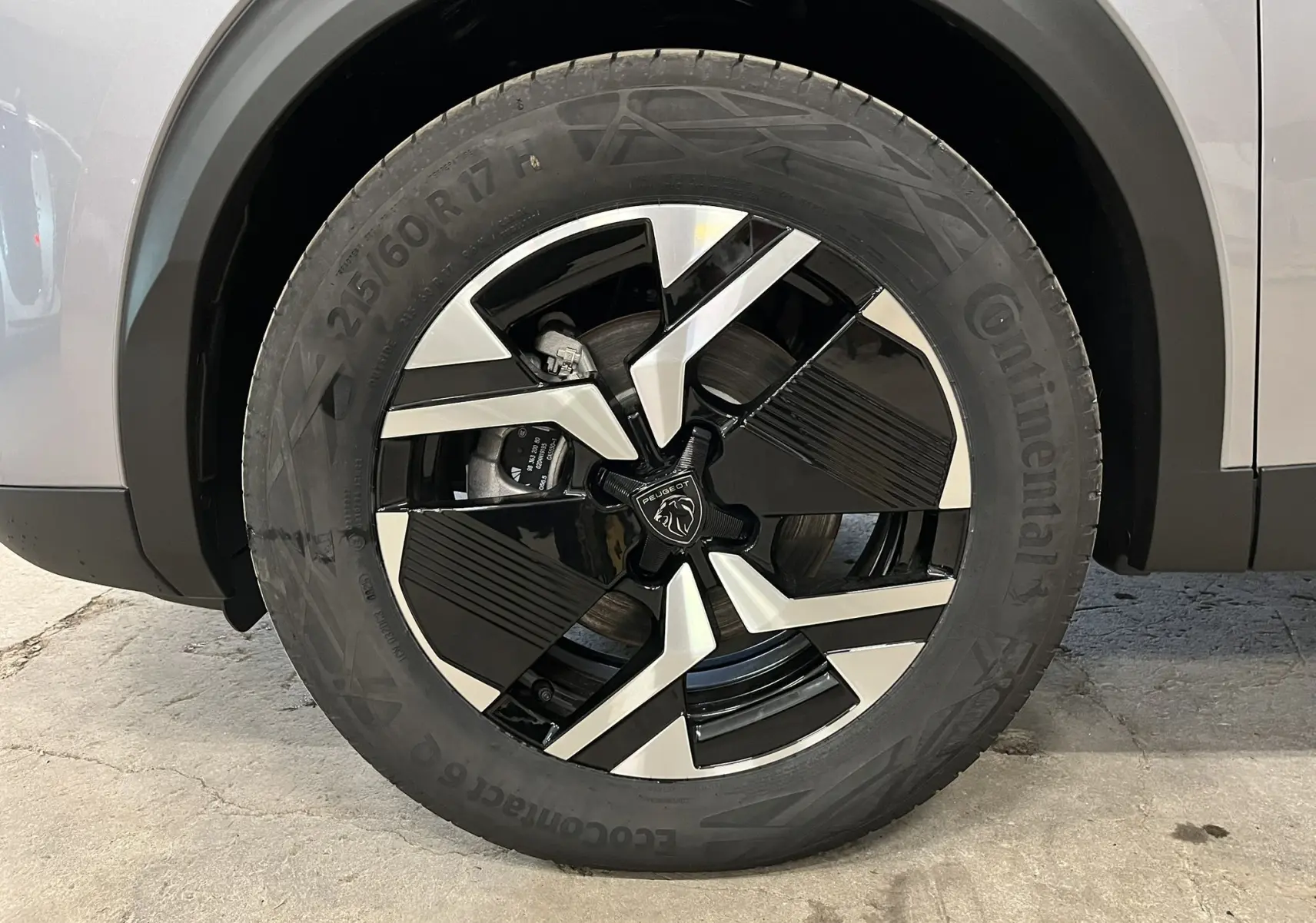 Gros plan sur la roue avant droite du Peugeot 2008 gris Artense, mettant en valeur la jante noire et argentée au design moderne.