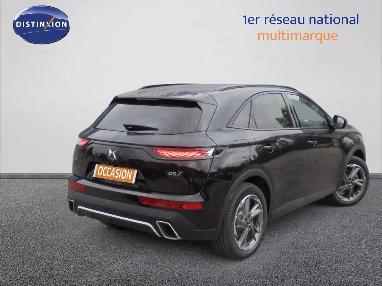 Vue 3/4 arrière droite du DS7 Crossback E-TENSE noir perle métal avec feux allumés et double sortie d'échappement intégrée.