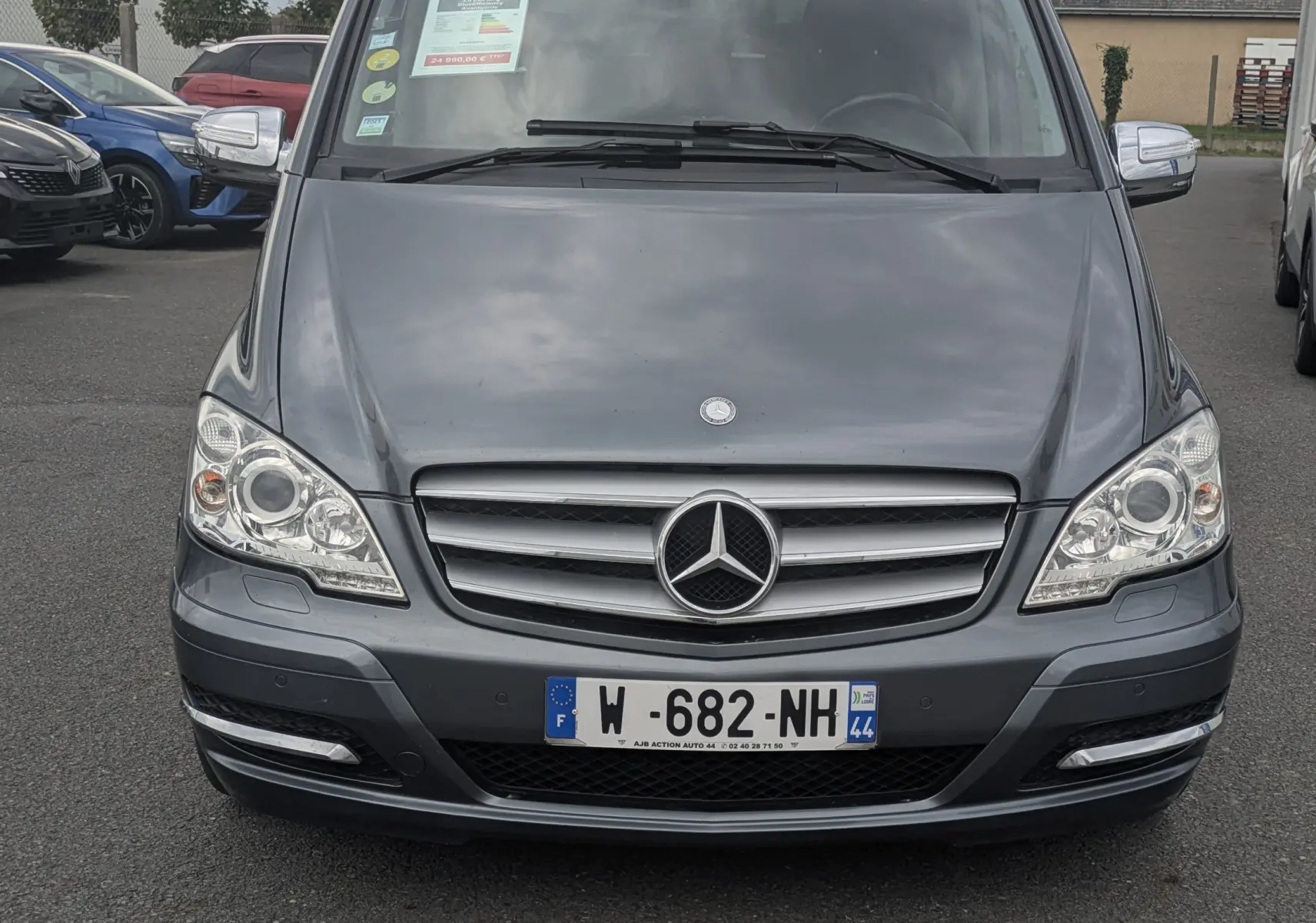 Vue frontale d'un Mercedes Viano gris 2012 avec calandre chromée et phares bi-xénon sur un parking extérieur.