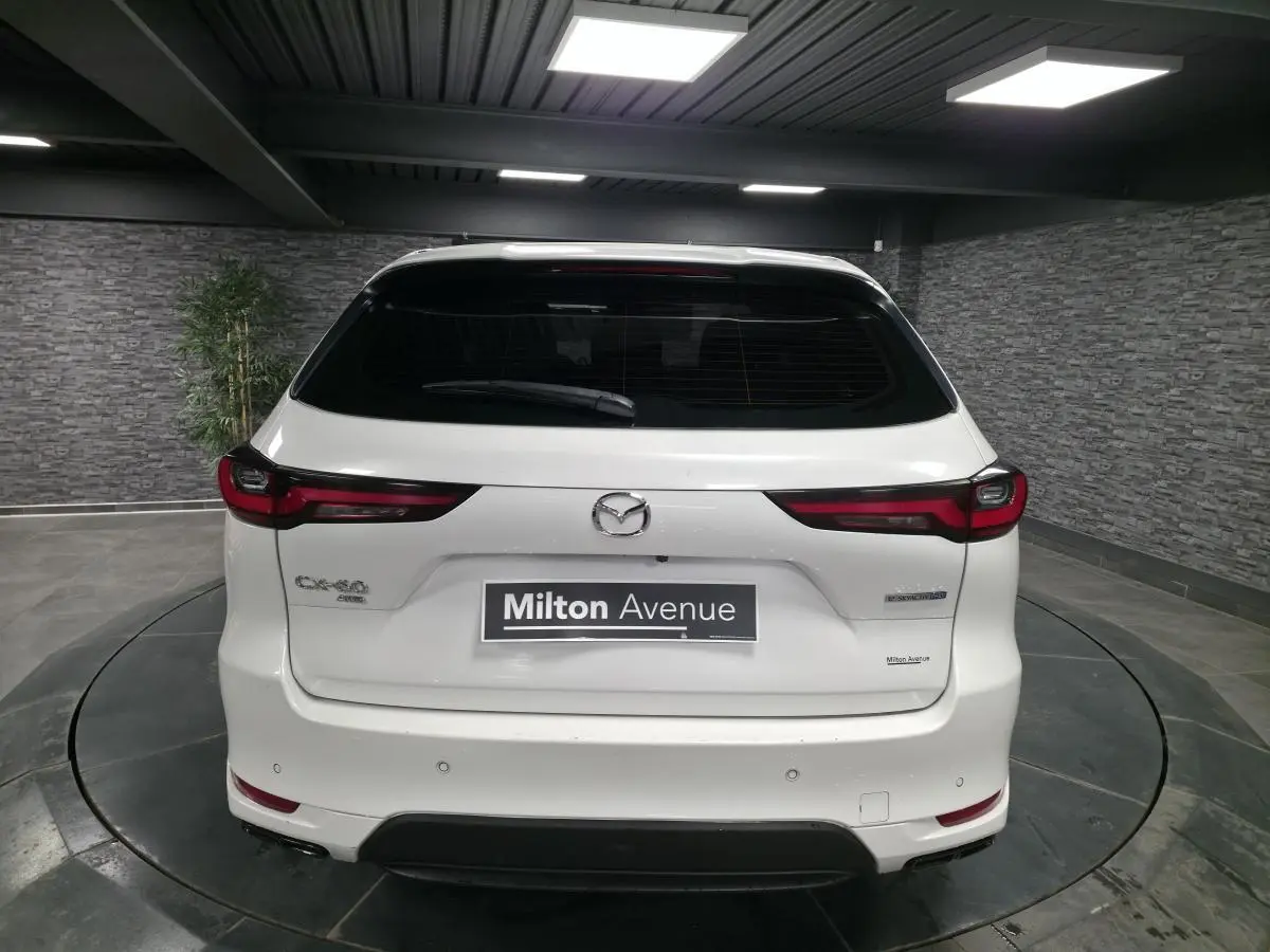 Vue arrière d'un Mazda CX-60 blanc 2023 hybride rechargeable avec feux arrière LED et logo central visible.
