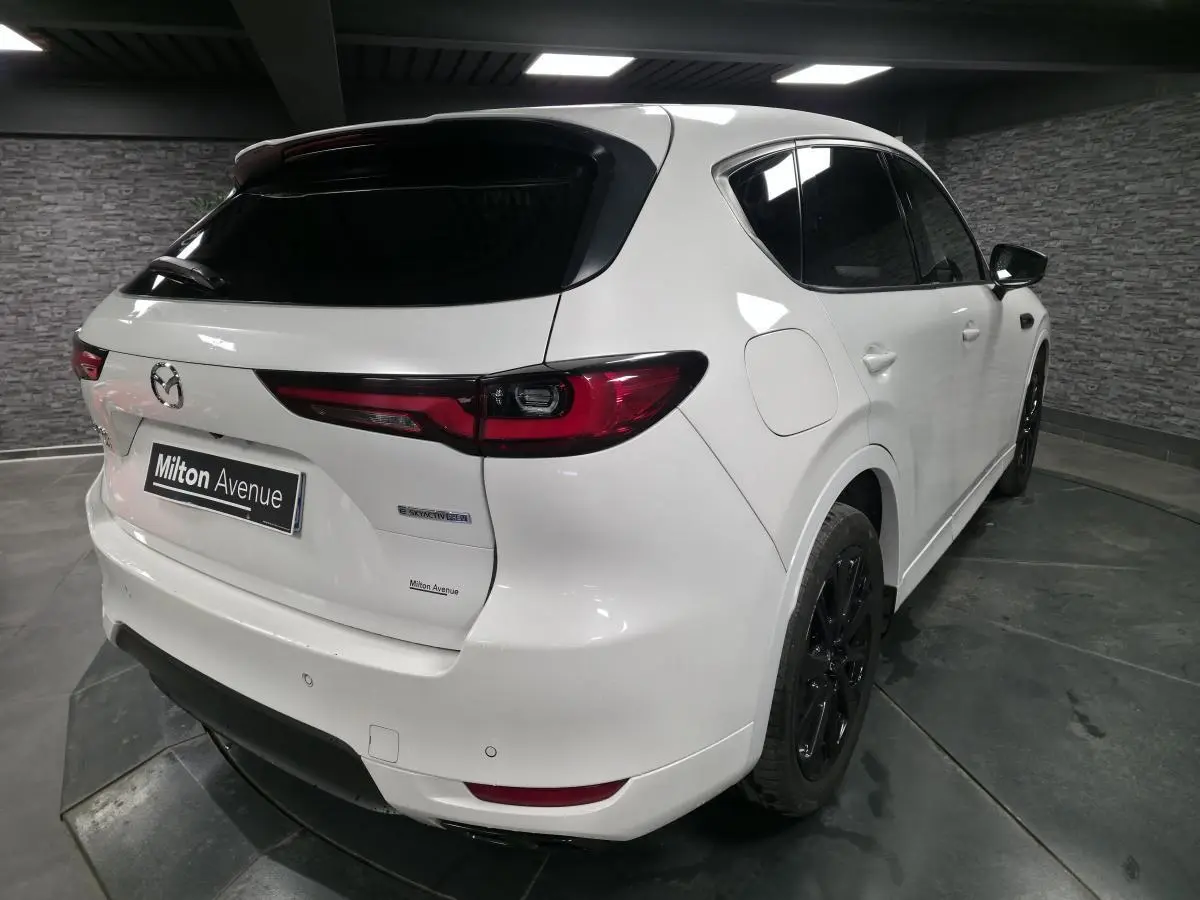 Vue 3/4 arrière droit du Mazda CX-60 blanc avec jantes noires et feux arrière LED dans un garage.
